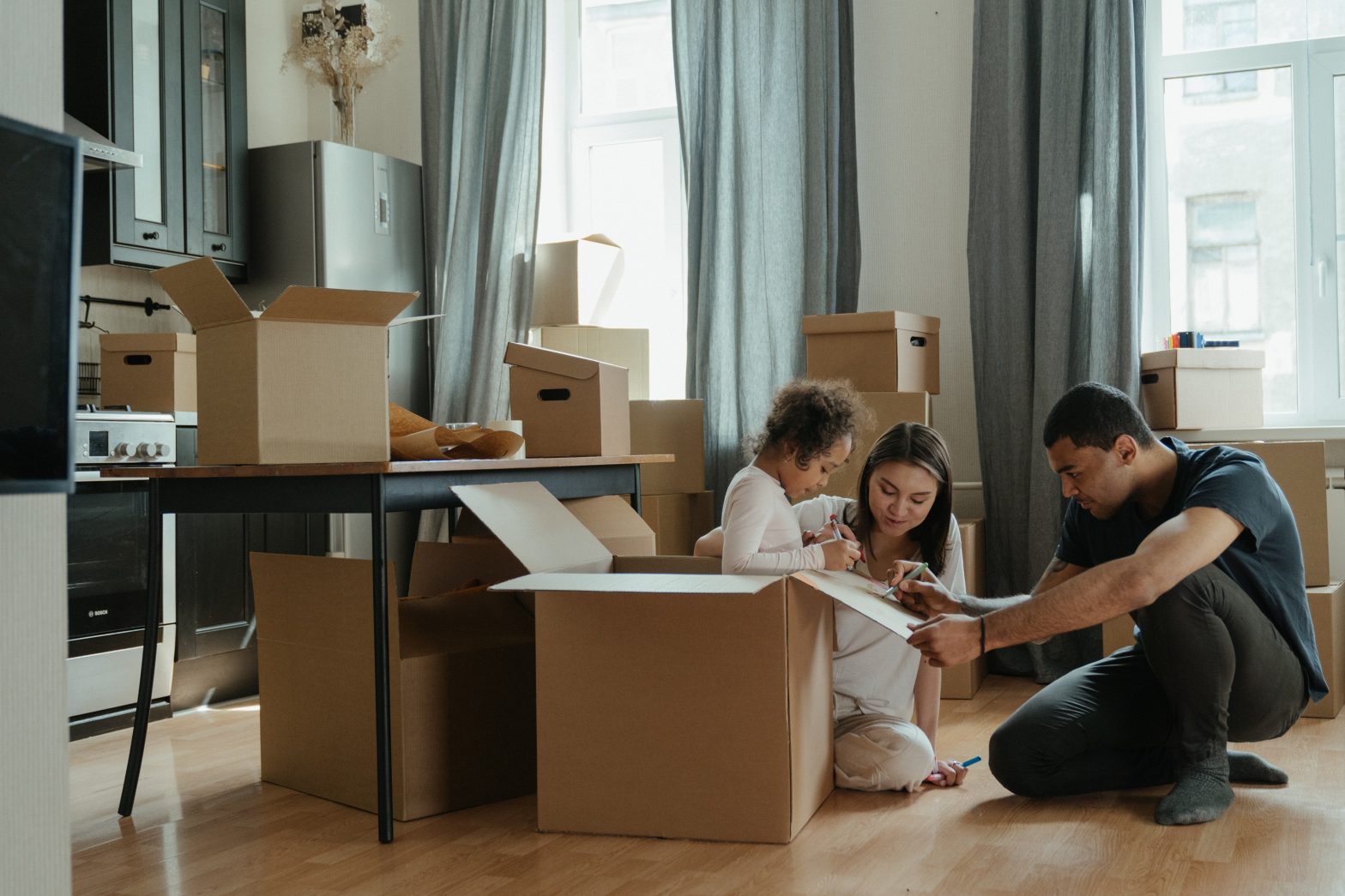Parents and their kid are surrounded with moving boxes